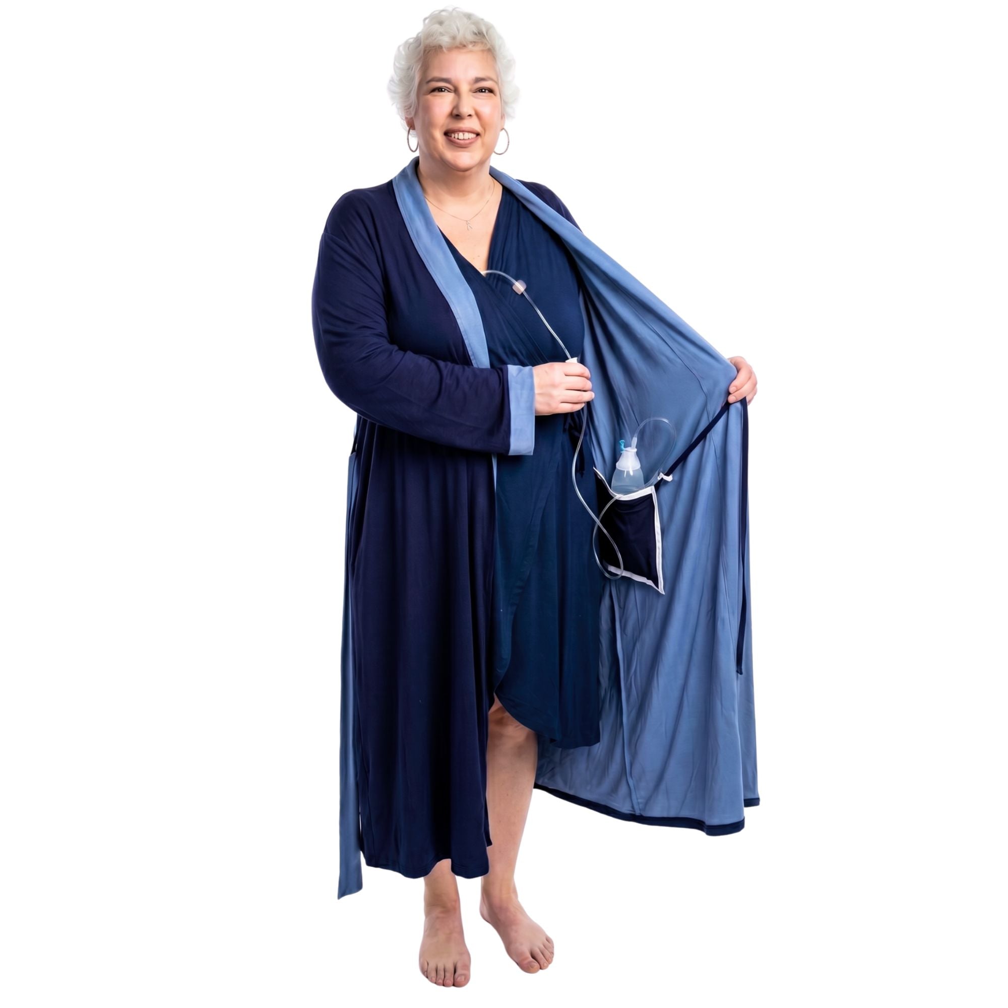 Woman wearing a navy two-toned recovery robe with an surgical bag going into the internal pocket on a white background