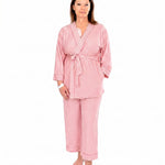 A woman wearing pink striped recovery  pajamas set against a white background