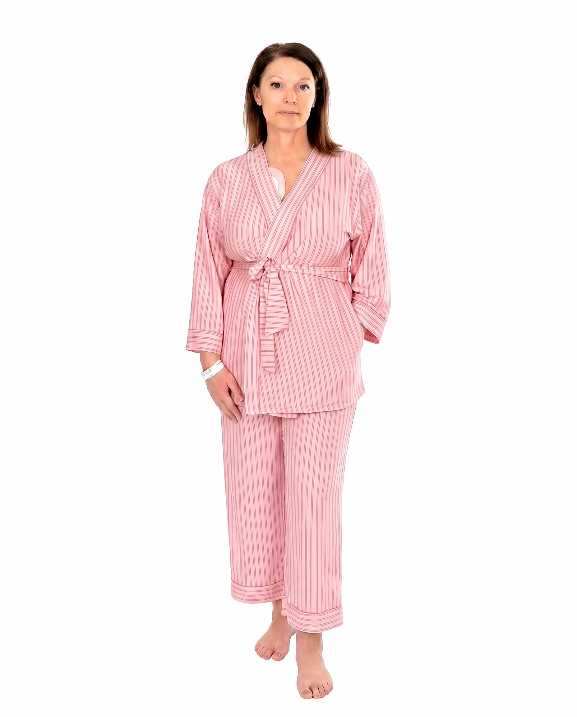 A woman wearing pink striped recovery  pajamas set against a white background