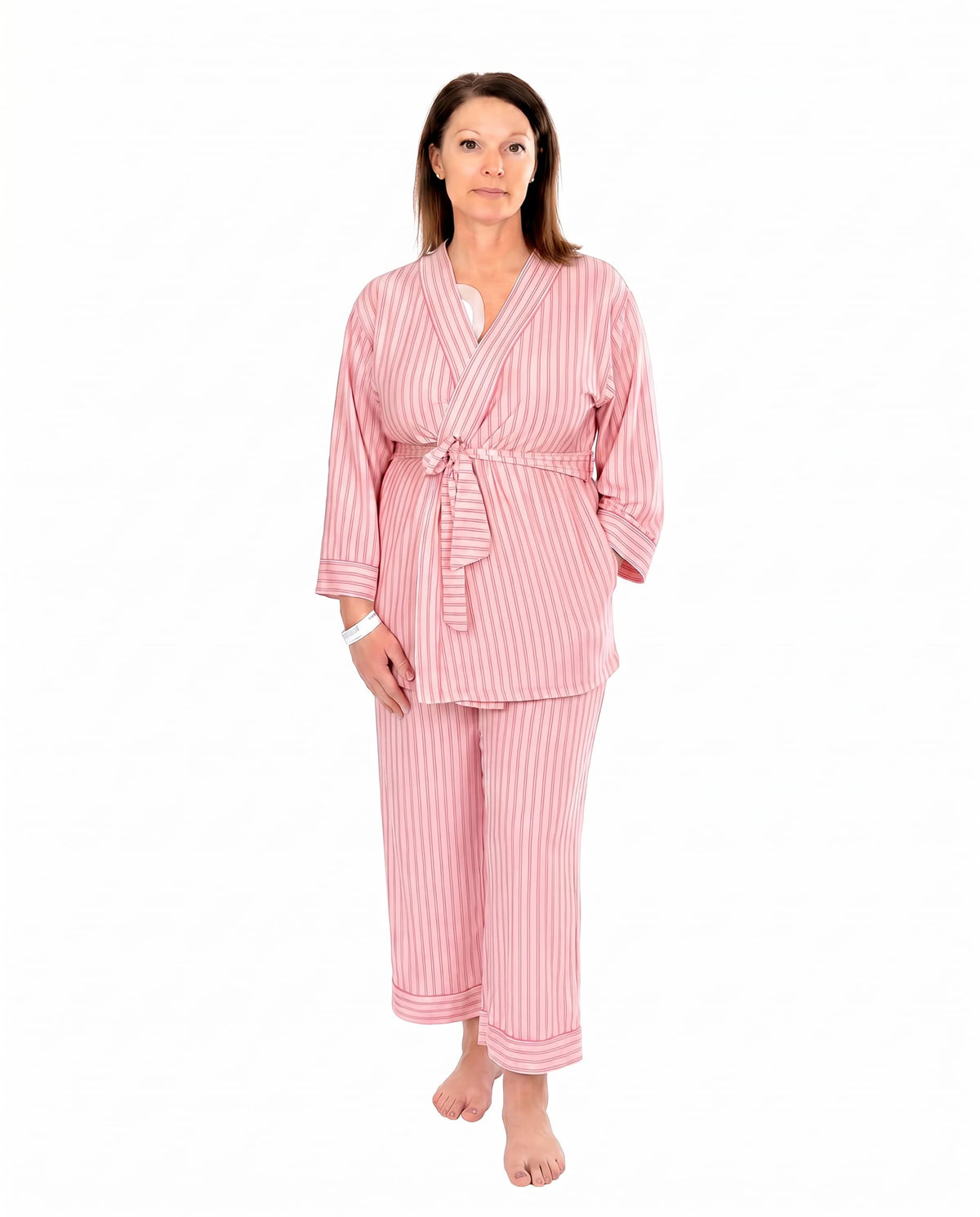 A woman wearing pink striped recovery  pajamas set against a white background