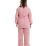 A woman viewed from the back wearing a pink vertically striped pajama set with a sash tie top and matching pants, standing against a plain white background.