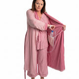 Woman wearing a pink recovery robe with an surgical bag going into the internal pocket on a white background