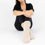 Person wearing oatmeal-beige cable knitted socks on a white background