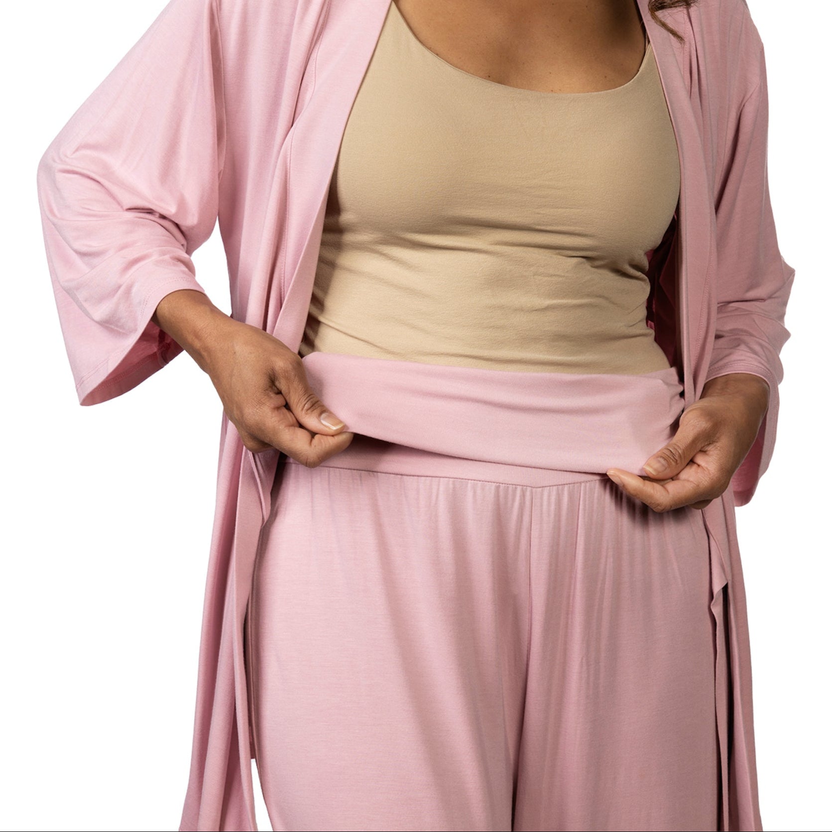 Person wearing a pink outfit with a beige top on a white background