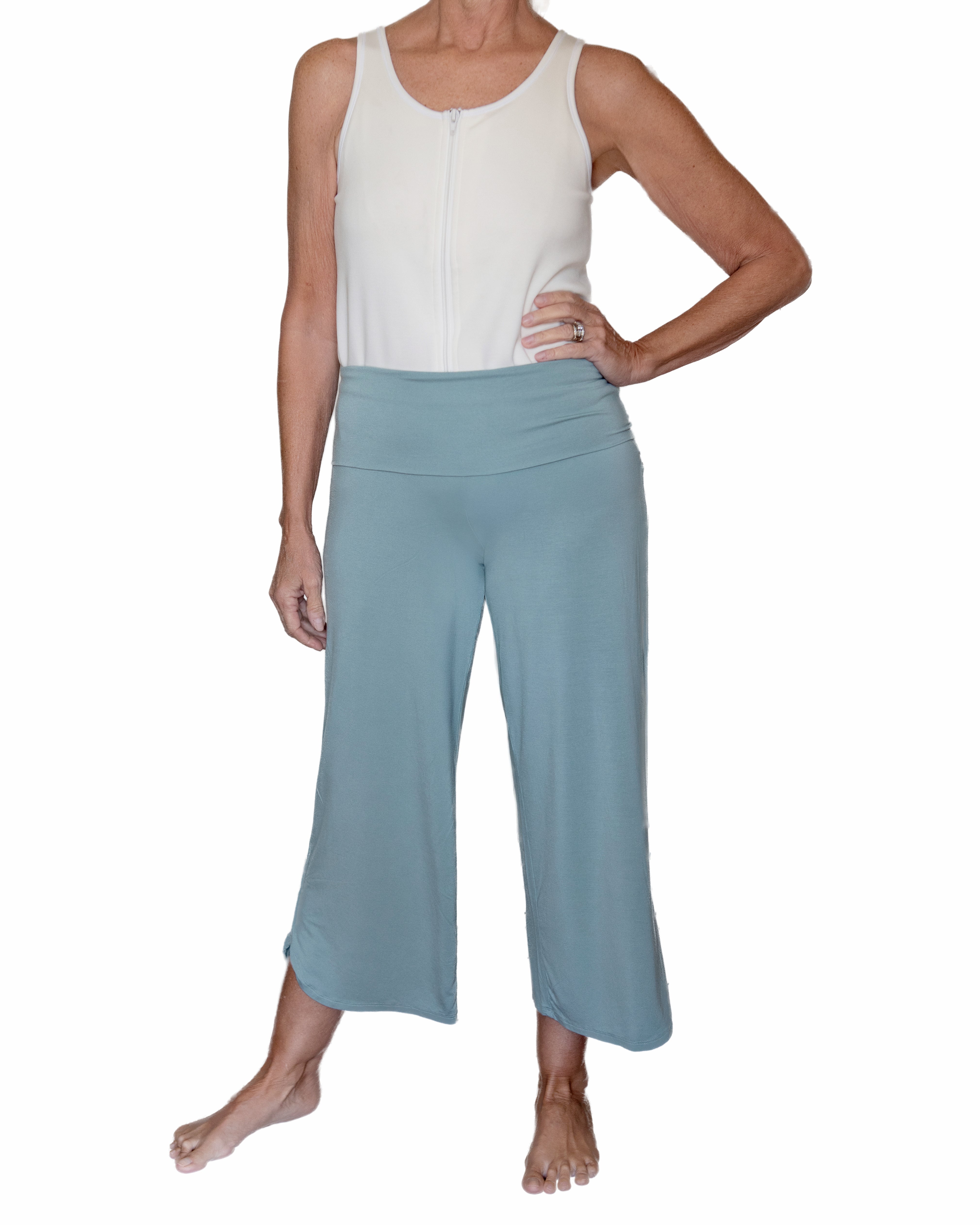 Woman wearing sage green pants highlighting the adaptive adjustable waistband that folds over against a white background
