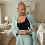woman wearing mastectomy pajamas highlighting the interior drain pocket in a living room background setting