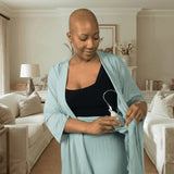 woman wearing mastectomy pajamas highlighting the interior drain pocket in a living room background setting