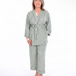 A woman modeling a two-piece sage green pajama set with vertical stripes, consisting of a long-sleeve tie-front robe and matching pants, against a plain white background.