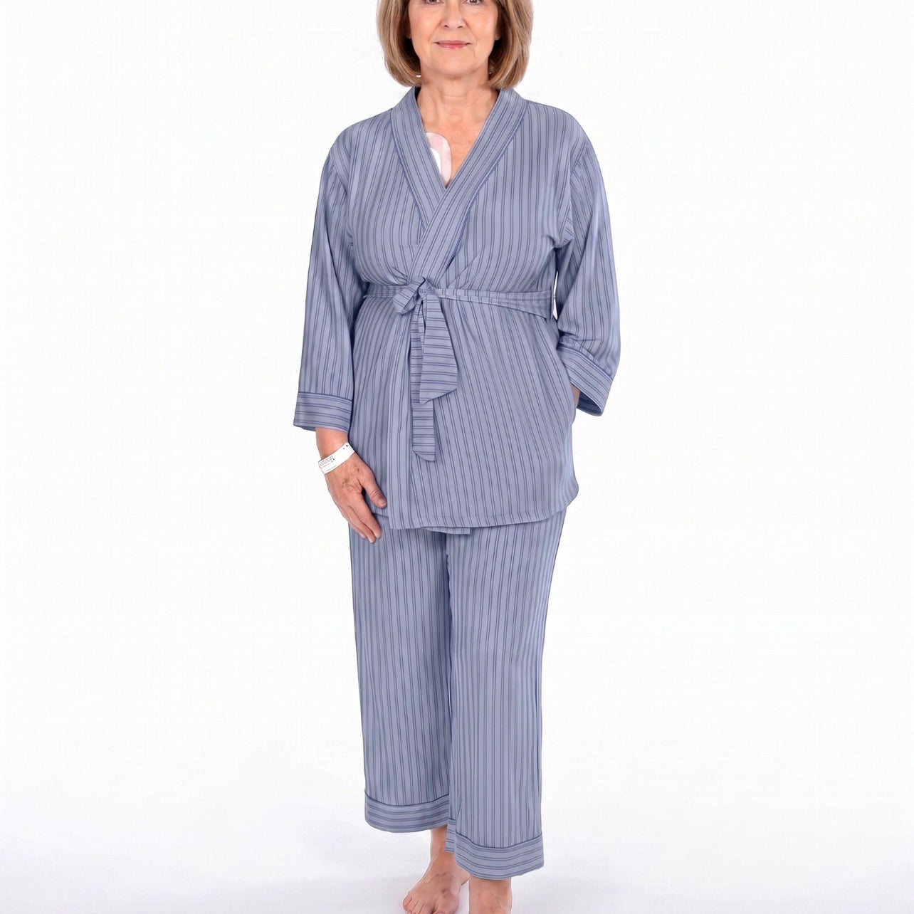 A woman modeling a two-piece navy blue pajama set with vertical stripes, consisting of a long-sleeve tie-front robe and matching pants, against a plain white background.