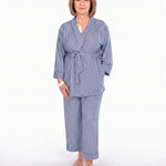 A woman modeling a two-piece navy blue pajama set with vertical stripes, consisting of a long-sleeve tie-front robe and matching pants, against a plain white background.