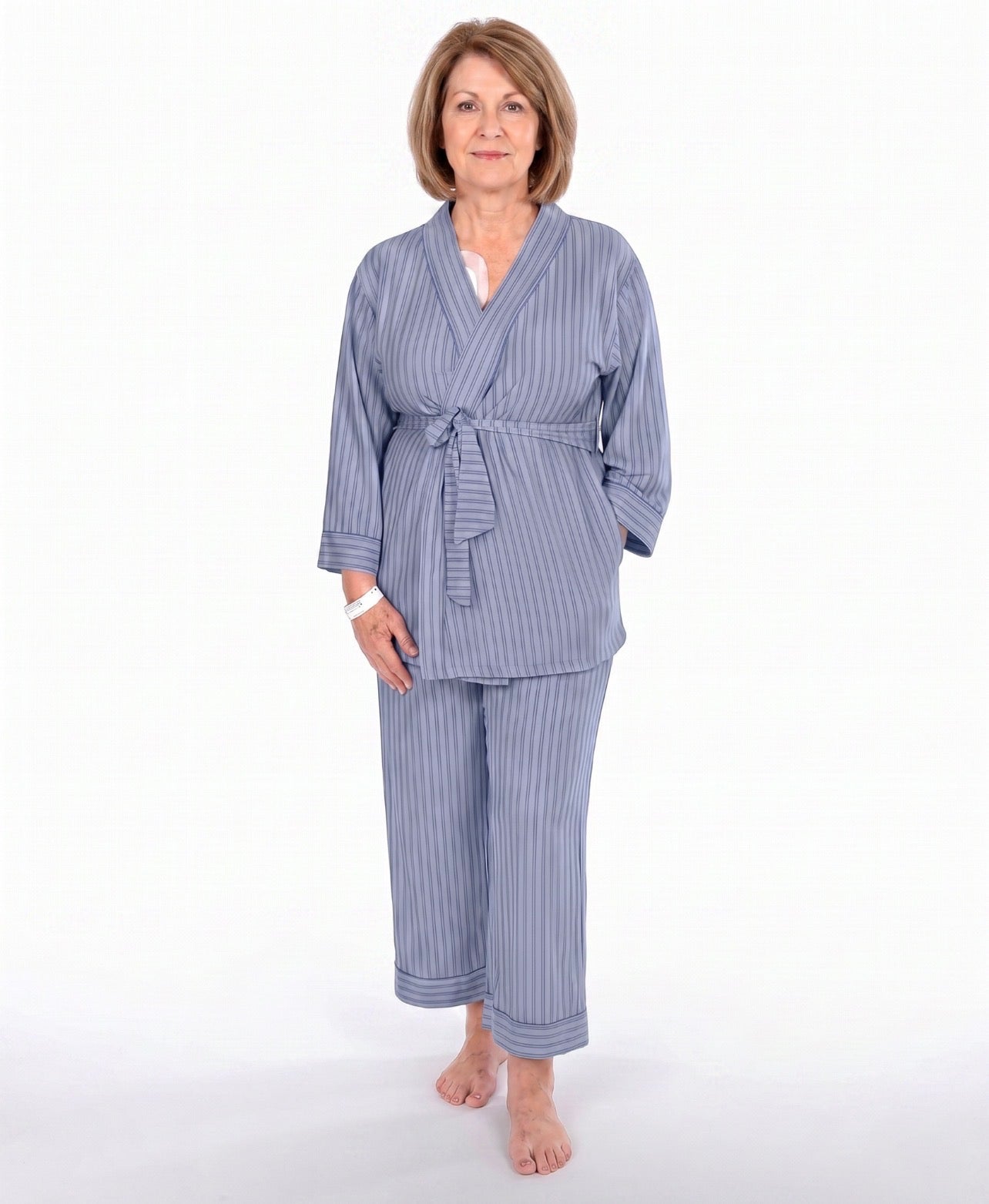 A woman modeling a two-piece navy blue pajama set with vertical stripes, consisting of a long-sleeve tie-front robe and matching pants, against a plain white background.