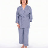 A woman modeling a two-piece navy blue pajama set with vertical stripes, consisting of a long-sleeve tie-front robe and matching pants, against a plain white background.