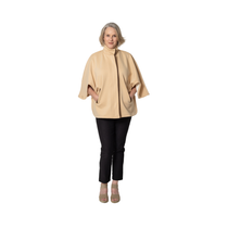 Woman wearing a beige poncho and black pants on a white background
