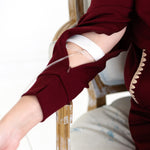 Close-up of a person wearing a mulberry long-sleeve top with cut-out arm zipper access for medical devices