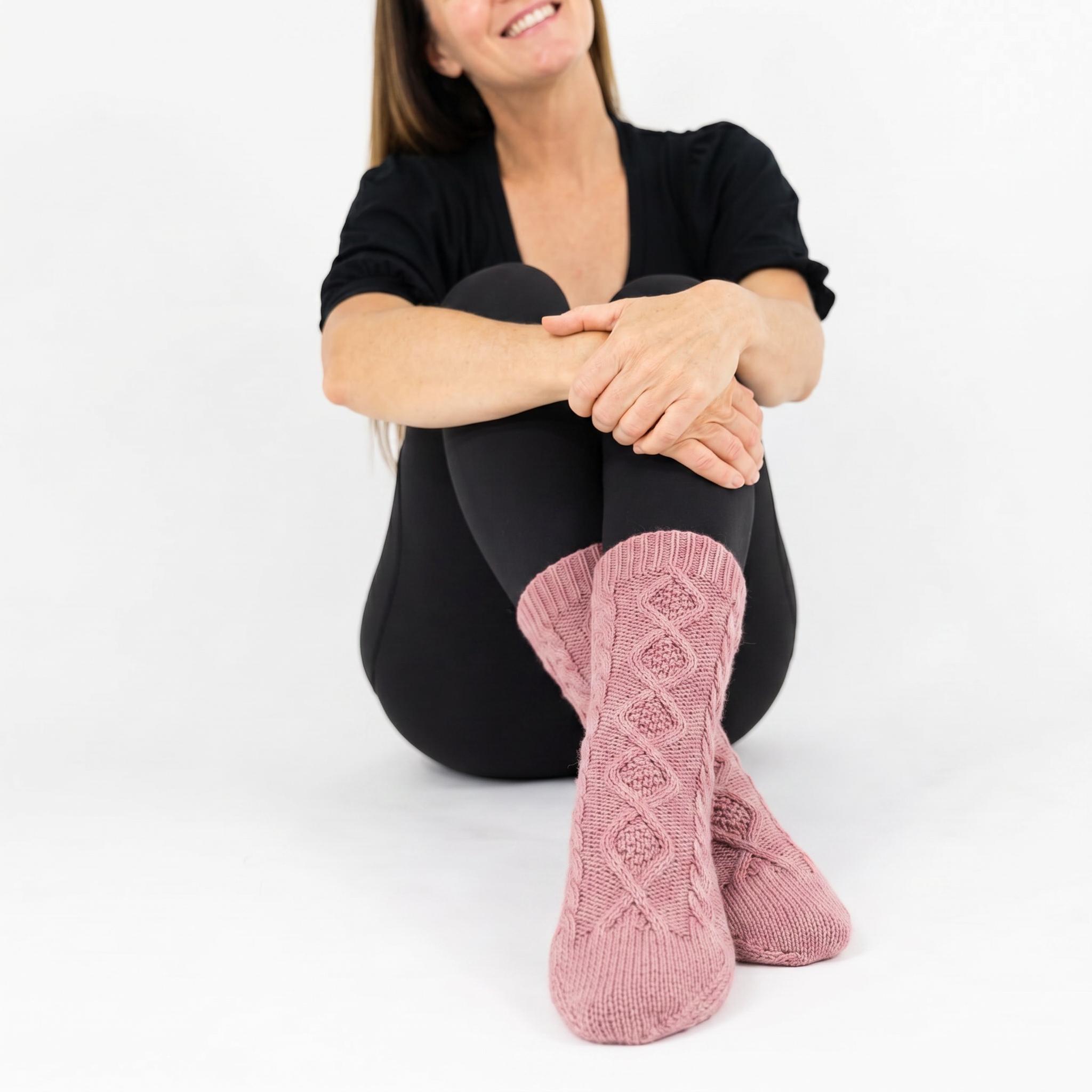 Woman wearing pink cable knit socks  against a white background