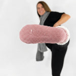 Woman kicking out her pink cable knit socks with white fleece interior cuffed at the top and non-slip grip bottoms against a white background