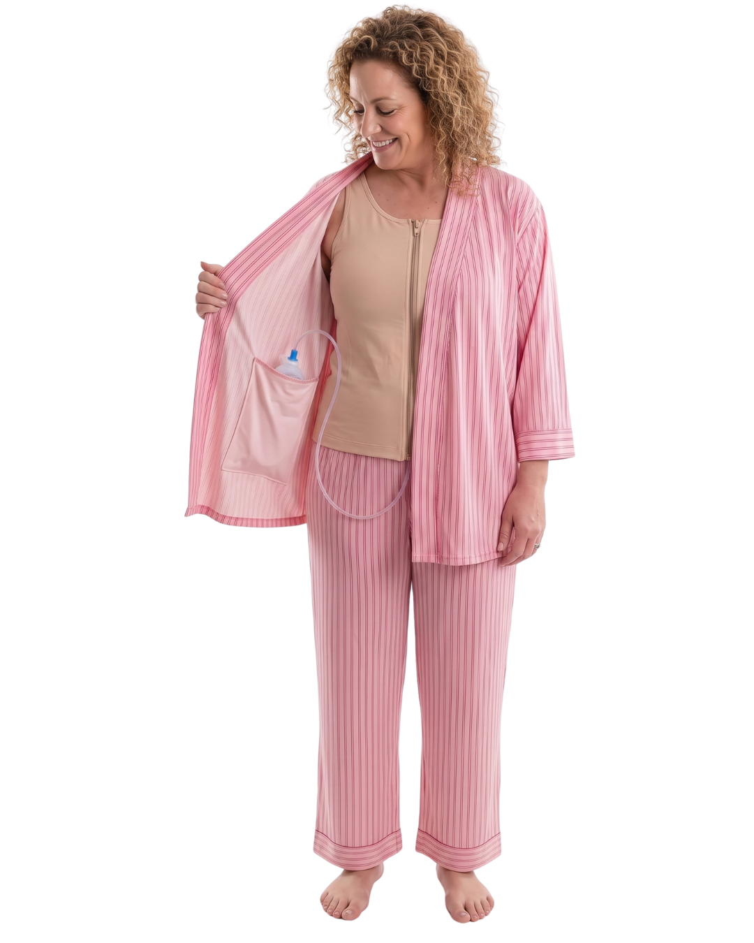 woman wearing pink striped recovery pajamas showing the interior drain pocket and how it fits a surgical bulb