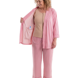 woman wearing pink striped recovery pajamas showing the interior drain pocket and how it fits a surgical bulb