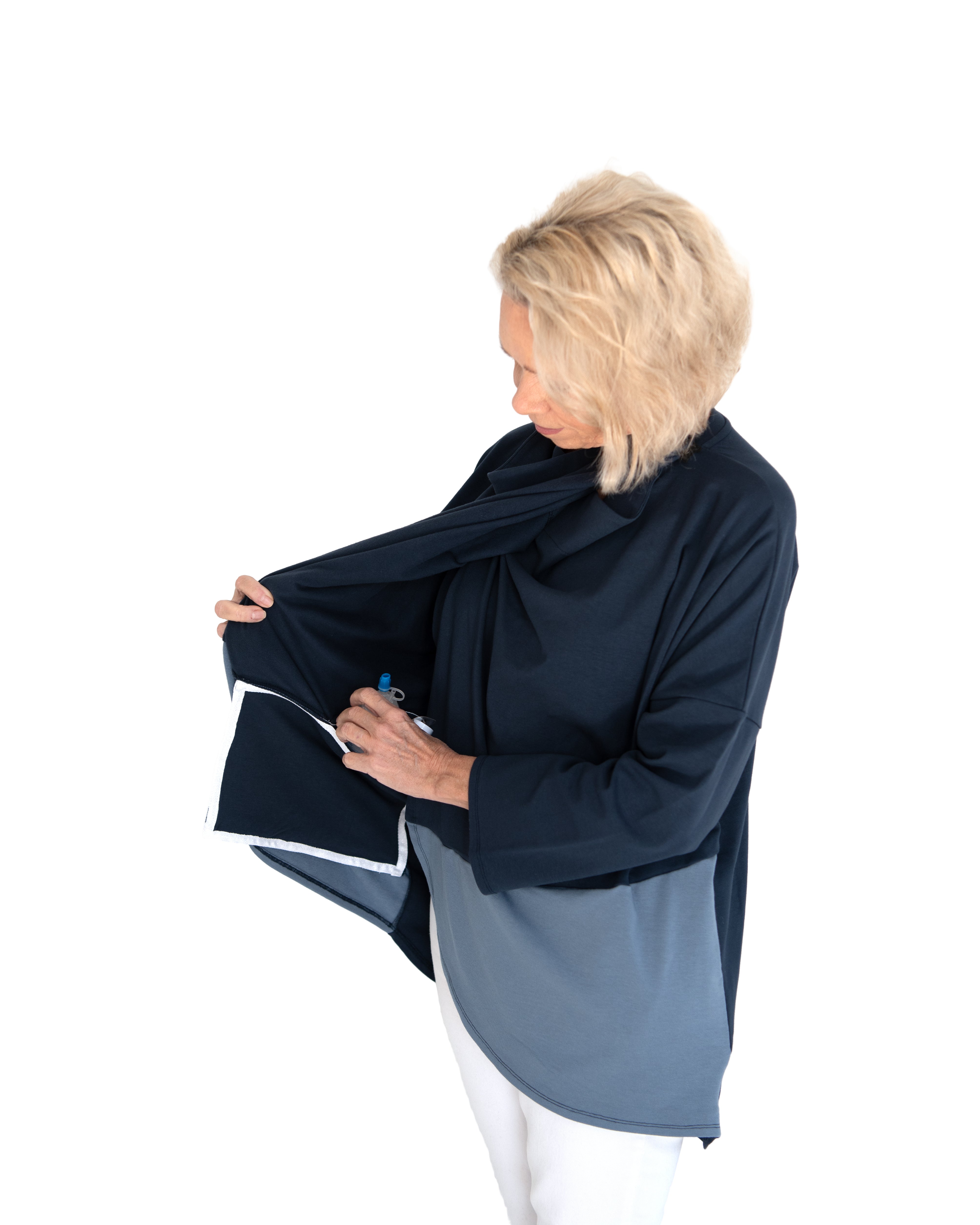 Woman wearing a navy blue wrap shirt worn open to show the interior pocket for surgical drains on a white background