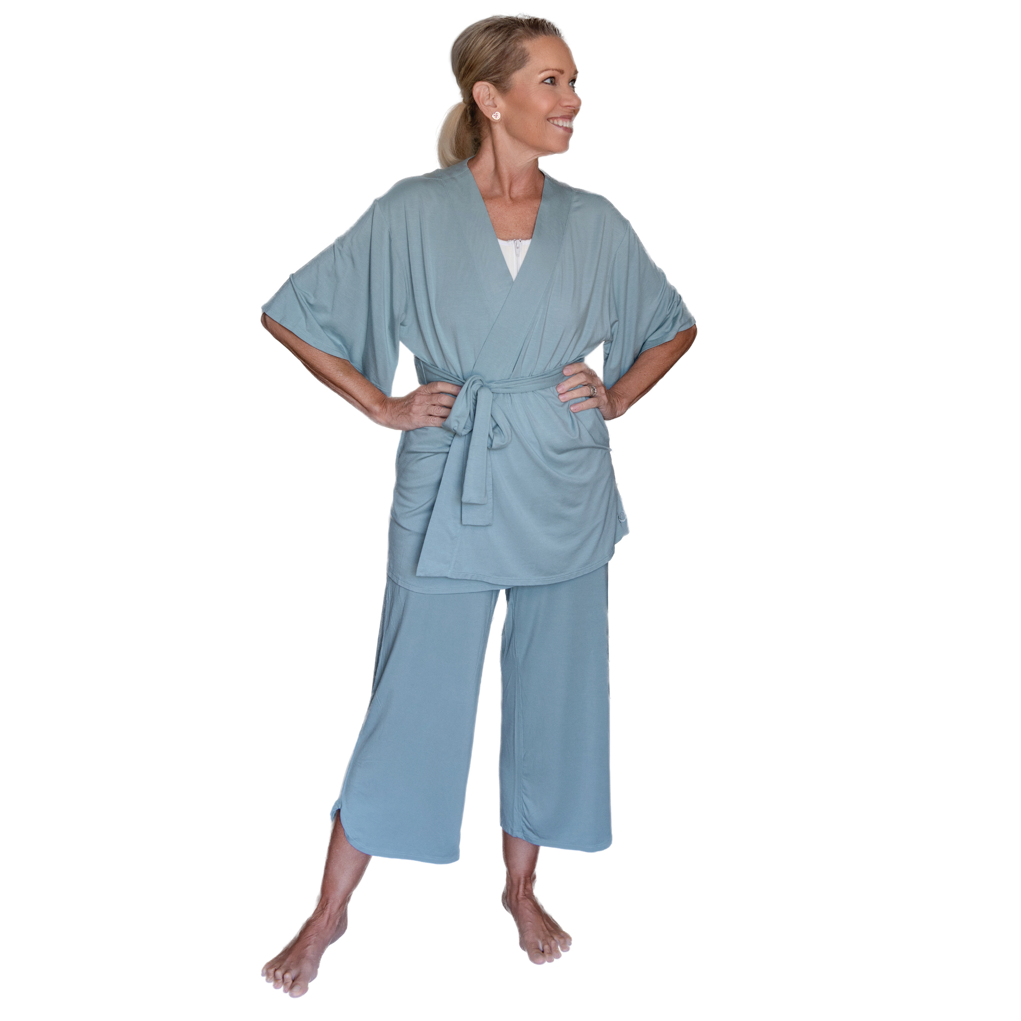 Woman wearing a sage green robe and pants set on a white background