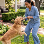 woman wearing a blue striped pajamas set playing with a dog in the front yard