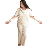 Woman wearing a cream-colored adaptive loungewear outfit with arm zippers for easy medical access on a white background