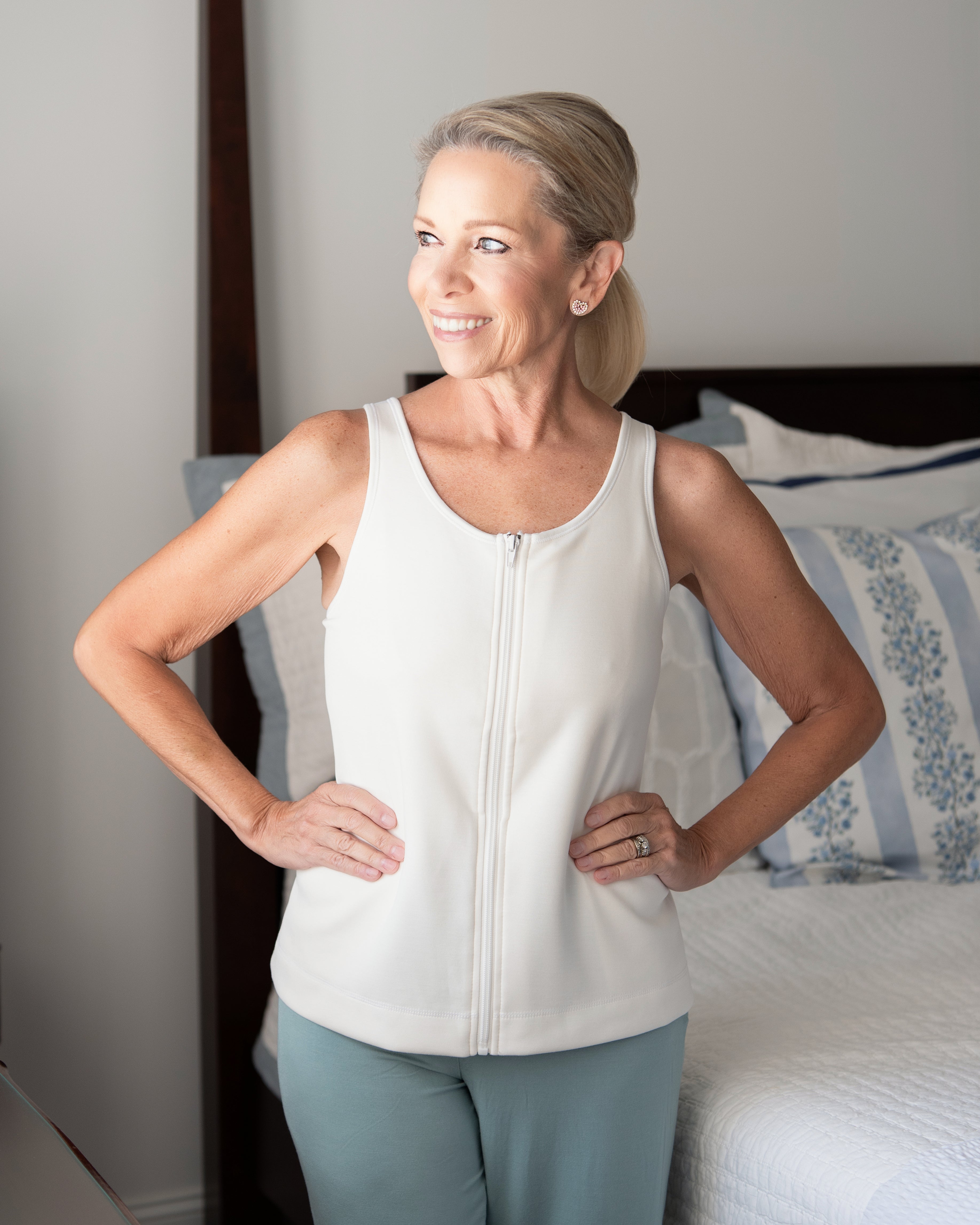 Woman wearing a white sleeveless top with zipper front for easy on and off during limited mobility after surgery