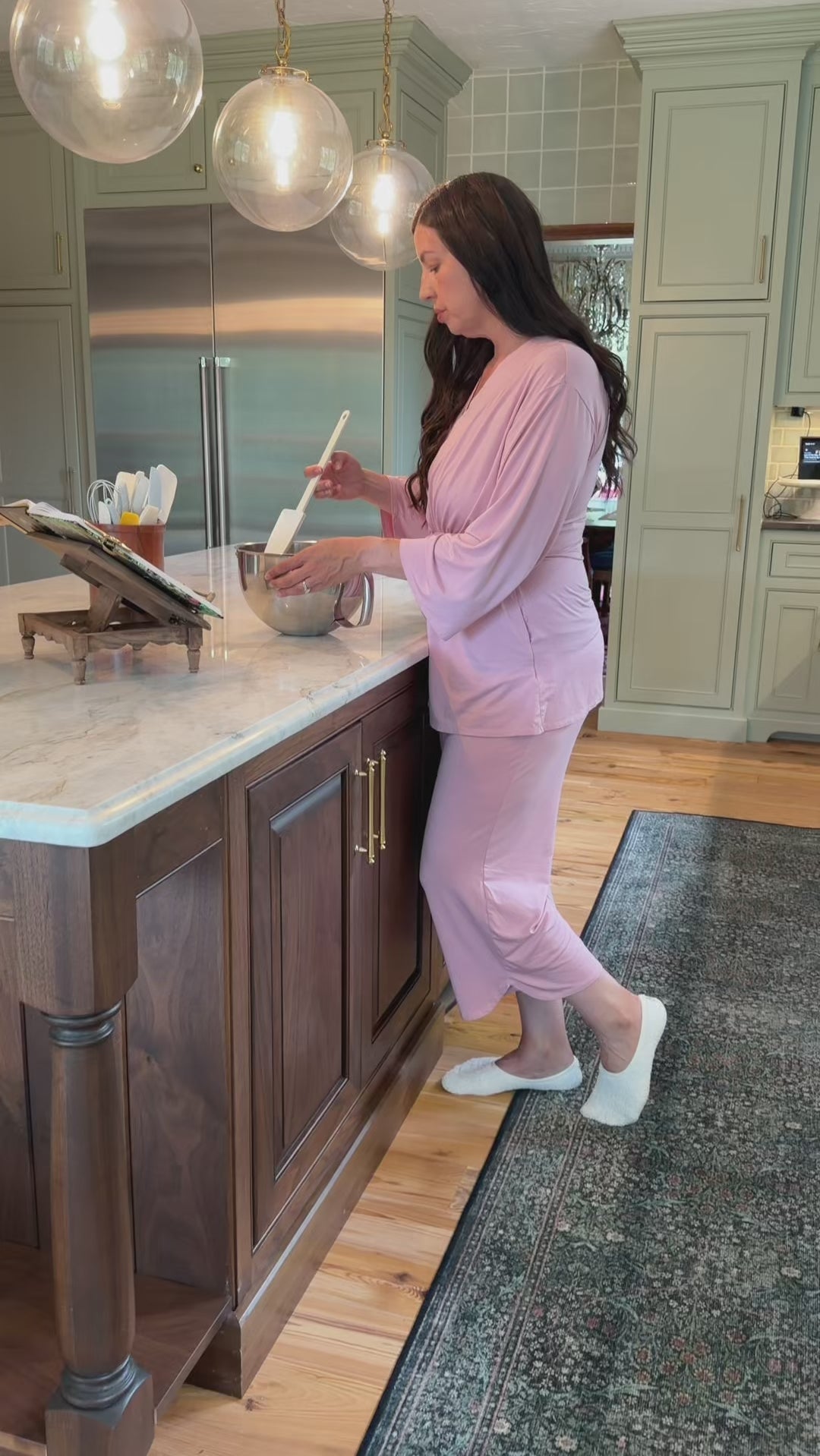 Woman in her kitchen wearing the KickIt Home Recovery Pajamas